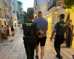 Dos agentes de la Guardia Civil llevan esposado al detenido.