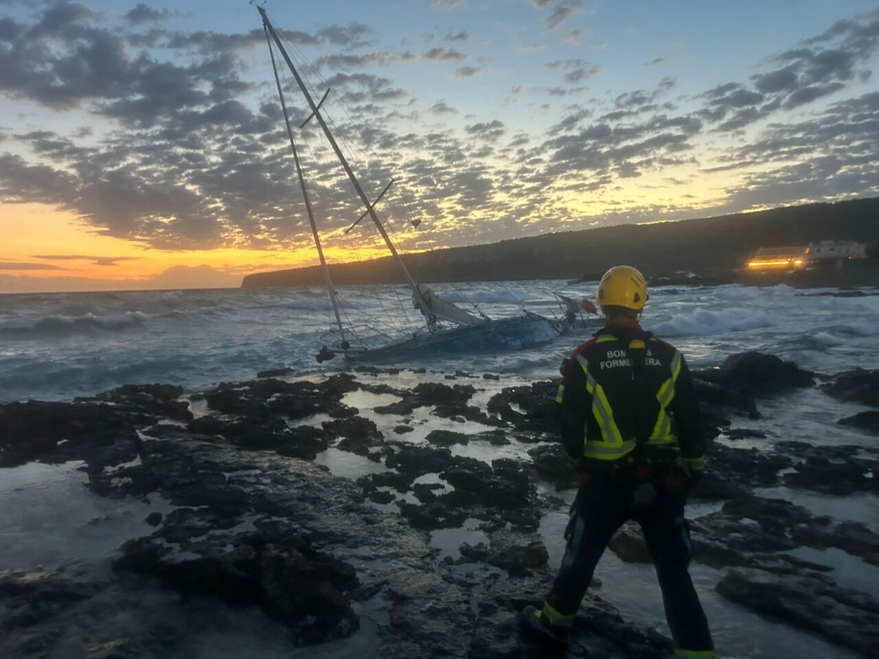 Un bombero frente al velero varado en las costas de Formentera.