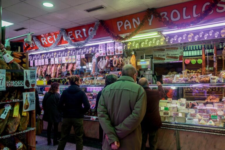 Varias personas esperan su turno en una charcutería.