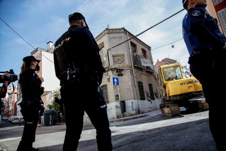 Varios agentes de Policía Nacional, frente a una retroexcavadora durante la demolición en octubre de 2022 de un edificio okupado en el madrileño barrio de Tetuán. (Europa Press)