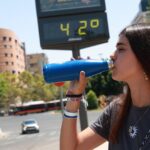 Una chica bebiendo agua un día de calor extremo.