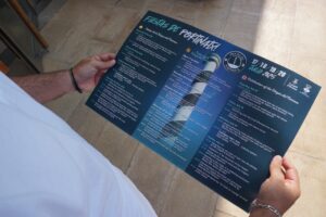 Persona mirando el cartel de las Festes de Portinatx. Ayuntamiento de San Joan