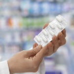 Persona sostiene una tableta de medicamentos.