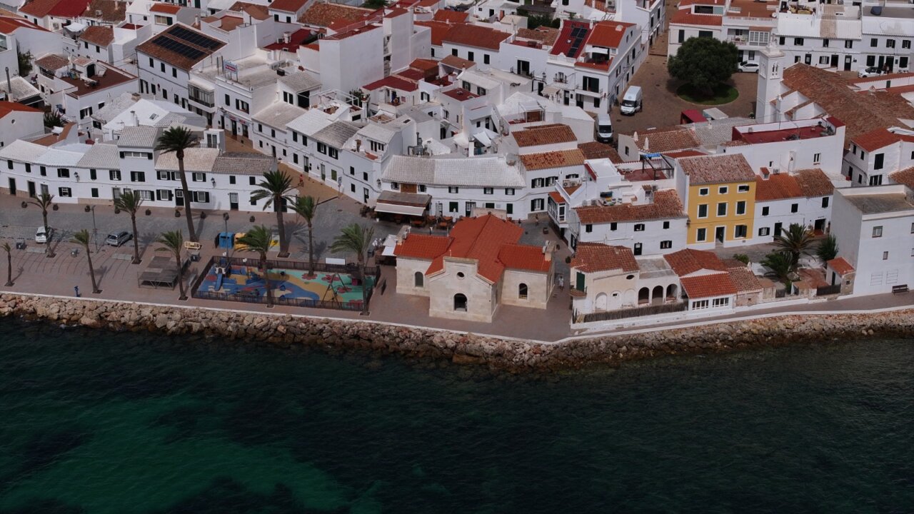 Vista aérea del puerto de Fornells con casas blancas y mar