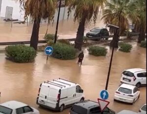 Hombre en patinete eléctrico desafiando una calle inundada en Ibiza