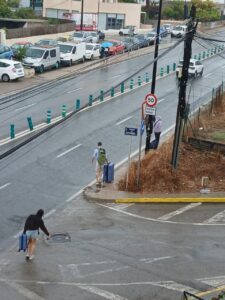 Personas caminando por una calle inundada en Ibiza con maletas