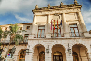 Fachada del Ayuntamiento de Gandia con banderas y palmeras