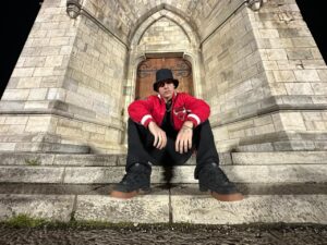 Aukan sentado en escaleras de piedra con chaqueta roja