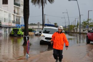 Hombre con chaqueta naranja camina por una calle inundada en Ibiza