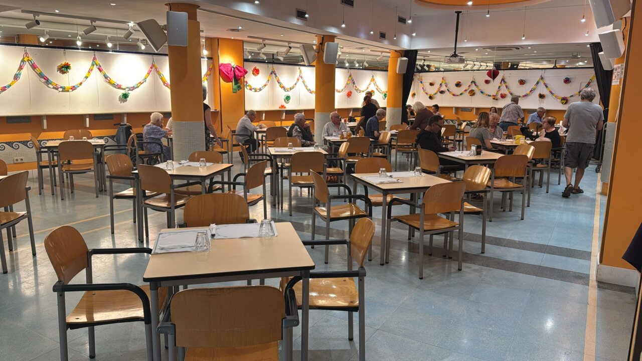 Cafetería del centro de ocio Llar Ibiza con mesas y personas mayores