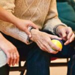 Mano de cuidador sosteniendo la mano de un anciano en residencia