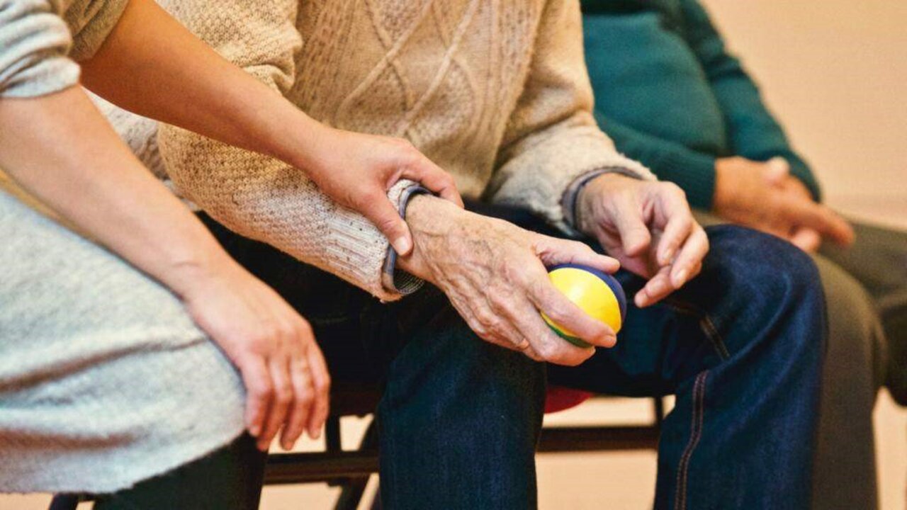 Mano de cuidador sosteniendo la mano de un anciano en residencia