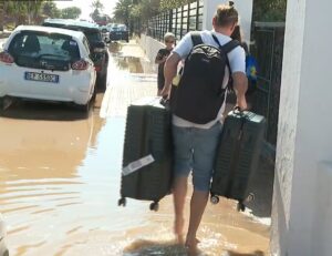 Persona cargando maletas en una calle inundada en Ibiza