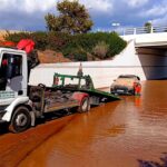 Grúa retirando un vehículo sumergido en agua tras inundaciones en Ibiza