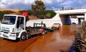 Grúa retirando un vehículo sumergido en agua tras inundaciones en Ibiza