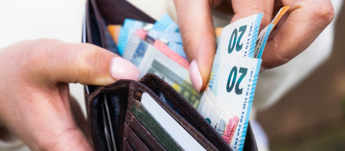 Persona sacando billetes de 20 euros de una cartera