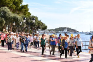 Grupo de personas mayores caminando junto al mar en un evento cultural