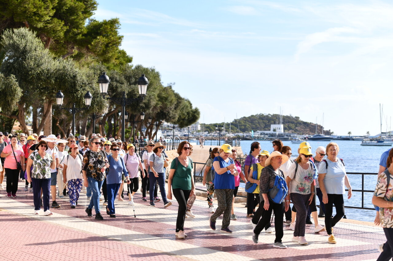 Grupo de personas mayores caminando junto al mar en un evento cultural