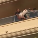Hombre en un balcón siendo sostenido por varias personas
