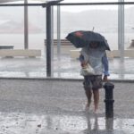 Persona caminando bajo la lluvia intensa en Ibiza con paraguas