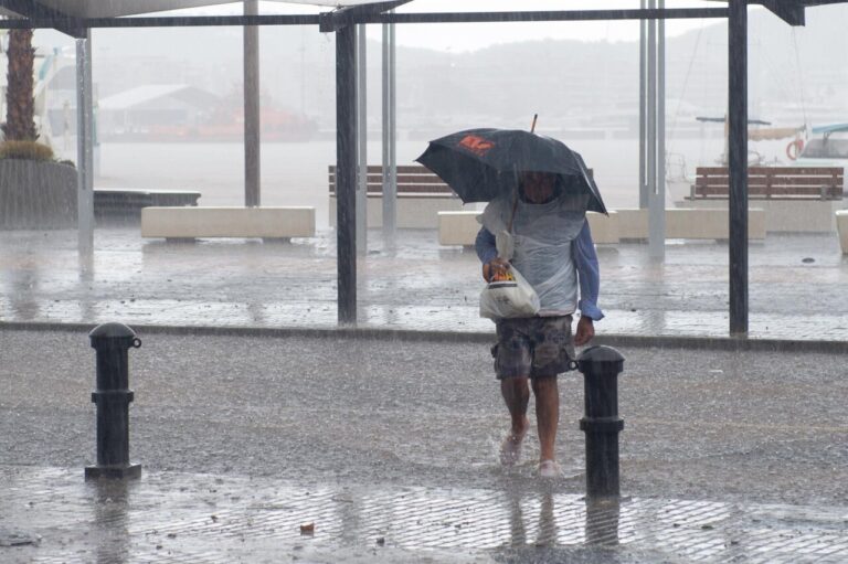 Persona caminando bajo la lluvia intensa en Ibiza con paraguas