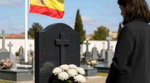 Mujer en un cementerio frente a una tumba con flores blancas.