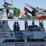 Barco de la flotilla humanitaria con banderas y voluntarios a bordo