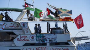 Barco de la flotilla humanitaria con banderas y voluntarios a bordo