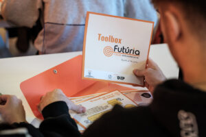 Persona sosteniendo un documento de Futúria + Jove en un entorno de trabajo.