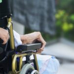 Persona mayor en silla de ruedas siendo asistida por un cuidador.