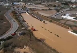Vista a&eacute;rea de una carretera inundada en Ibiza con veh&iacute;culos de emergencia.