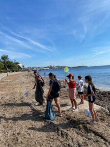 Grupo de j&oacute;venes voluntarios limpiando la playa de Ibiza