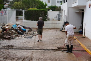 Dos hombres limpiando un área afectada por lluvia con escombros