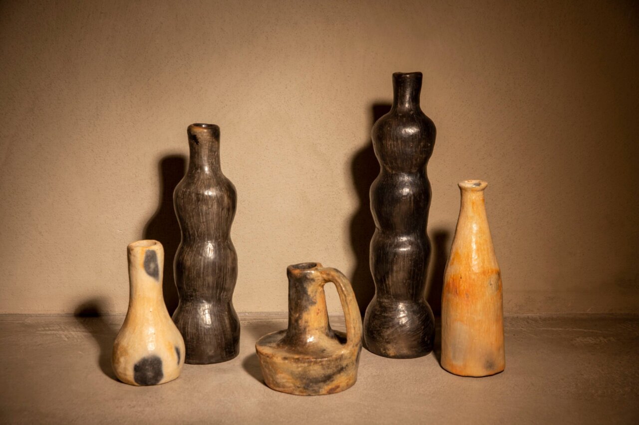 Vasos de cer&aacute;mica de diferentes formas y colores en un fondo neutro