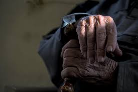 Manos de un anciano sosteniendo un bastón con luz suave