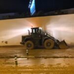 Maquinaria pesada trabajando en una obra durante la noche.
