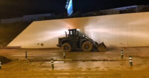 Maquinaria pesada trabajando en una obra durante la noche.