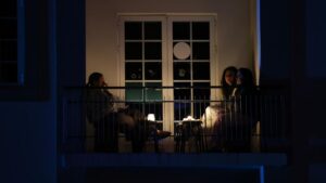 Tres mujeres sentadas en un balc&oacute;n iluminado por velas