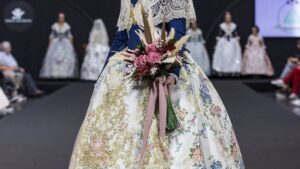 Modelo vistiendo traje tradicional valenciano con flores en la mano