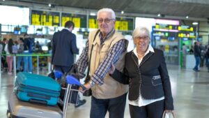 Pareja de jubilados en un aeropuerto con maletas listas para viajar.