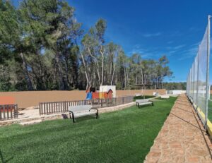 Vista de un parque infantil rodeado de árboles y césped