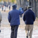Tres pensionistas caminando por un parque en oto&ntilde;o.