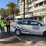 Tres agentes de la policía local interactuando junto a un coche patrulla