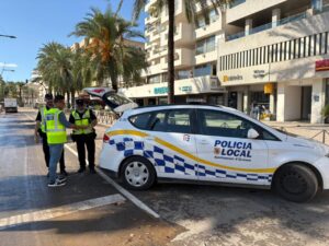 Tres agentes de la policía local interactuando junto a un coche patrulla