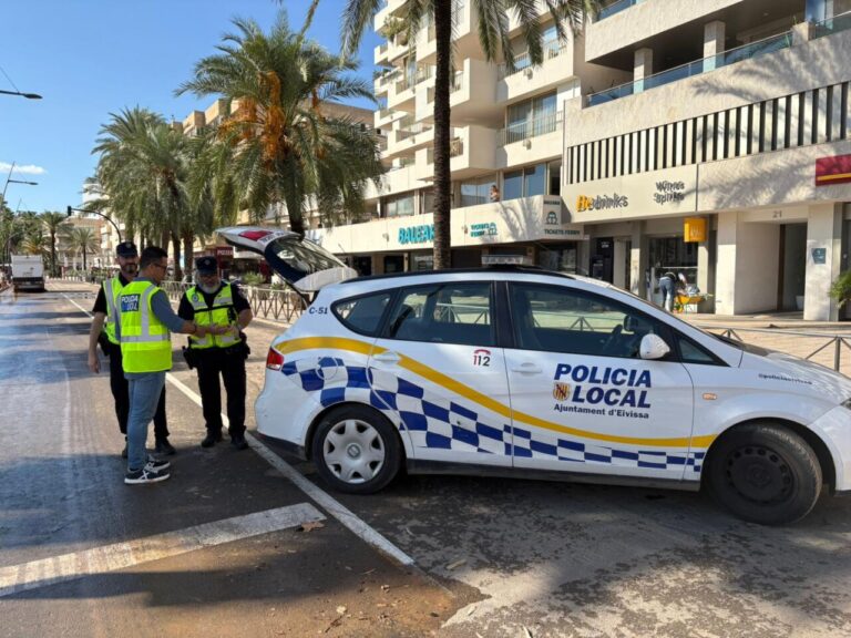 Tres agentes de la policía local interactuando junto a un coche patrulla