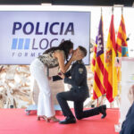 Un oficial de policía se arrodilla mientras besa a su pareja en un evento.