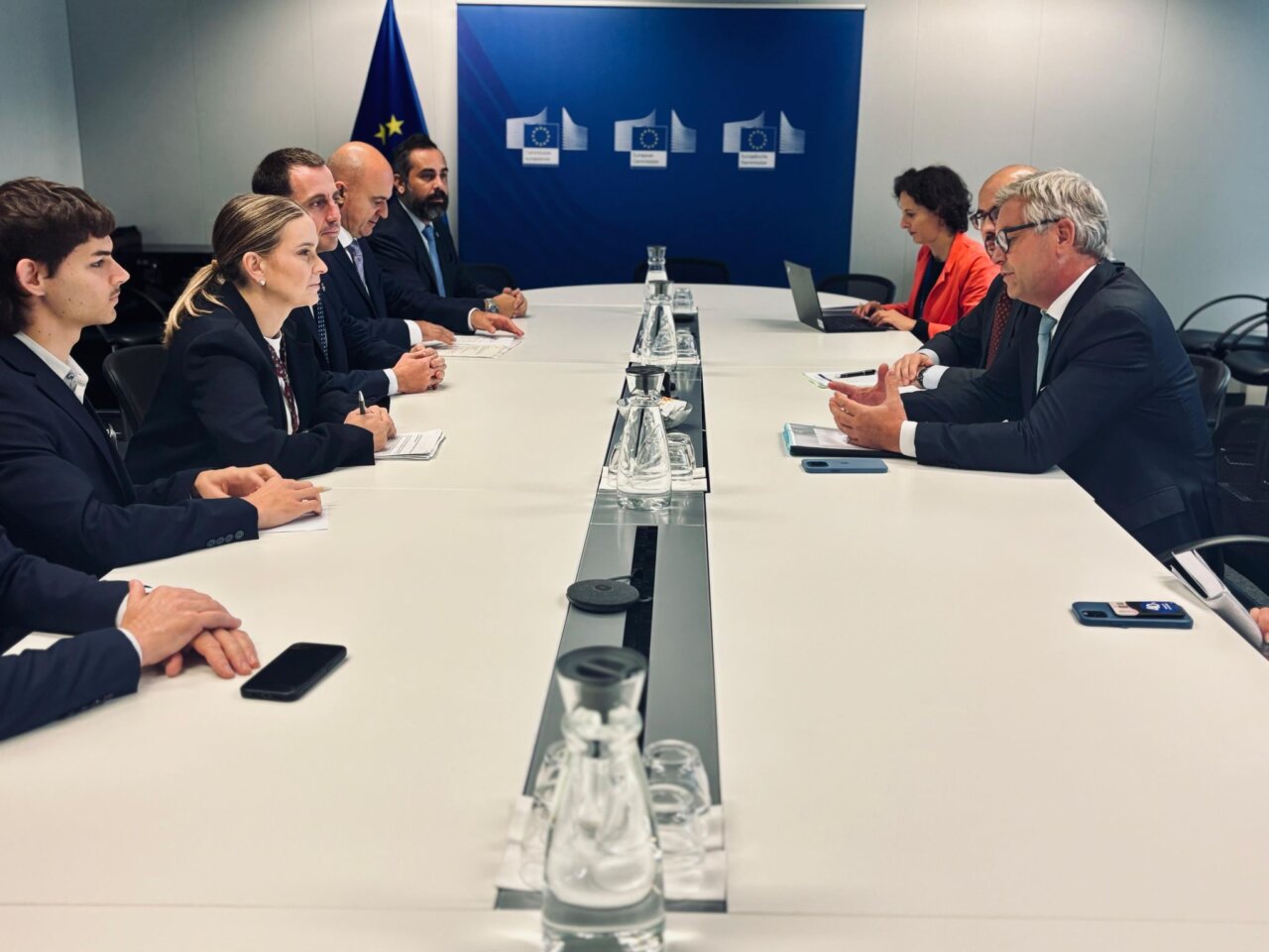 Reunión de funcionarios en un entorno formal con banderas de la UE.