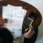 Persona revisando documentos y calculadora sobre una mesa