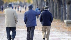 Tres jubilados caminando por un parque en otoño