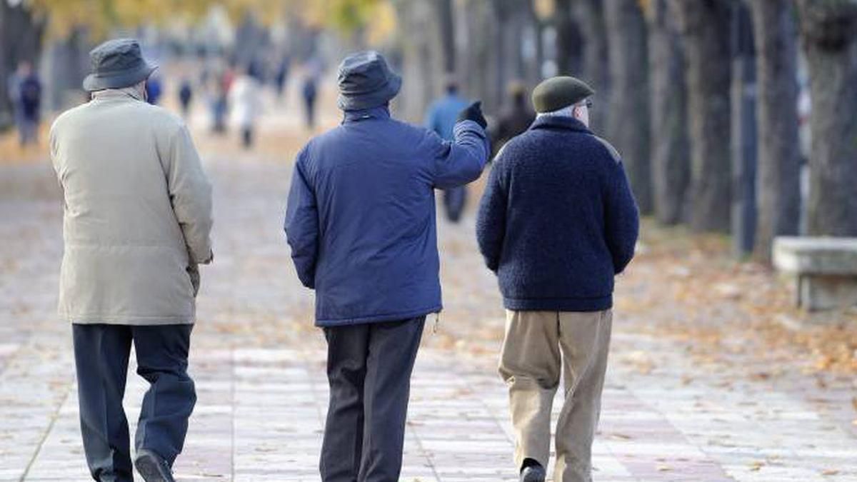 Tres jubilados caminando por un parque en oto&ntilde;o